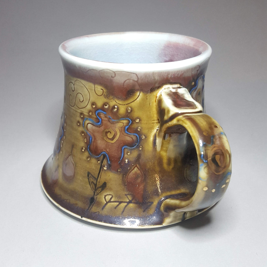 Decorative ceramic mug with artistic design on a plain background