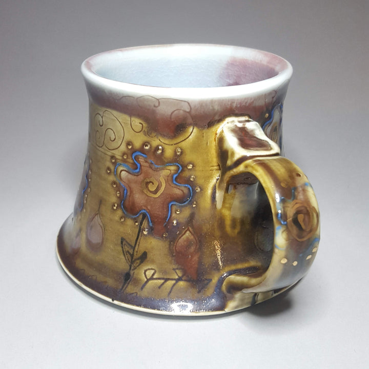 Decorative ceramic mug with artistic design on a plain background