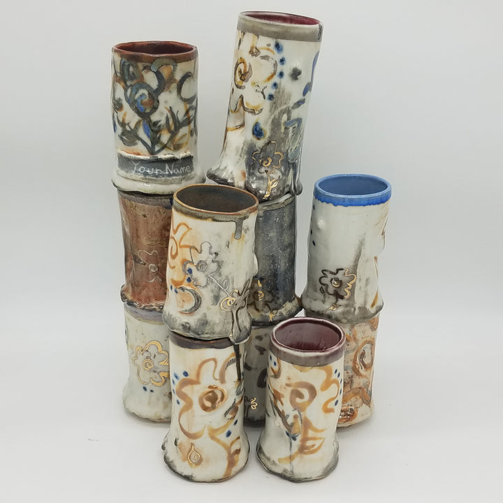 Stack of ceramic tubes with various patterns and colors on a white background