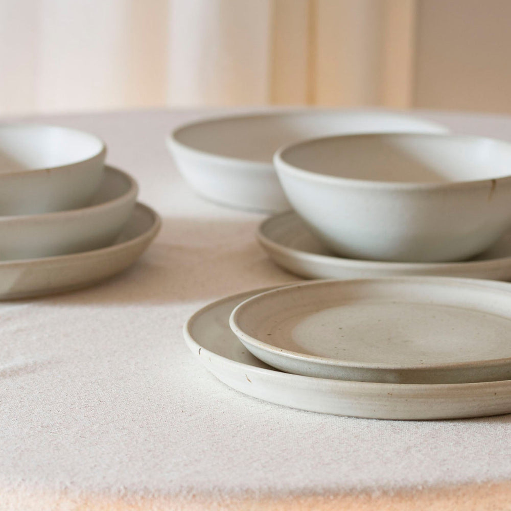 Set of ceramic bowls and plates on a neutral background - Dinnerware focused pottery class