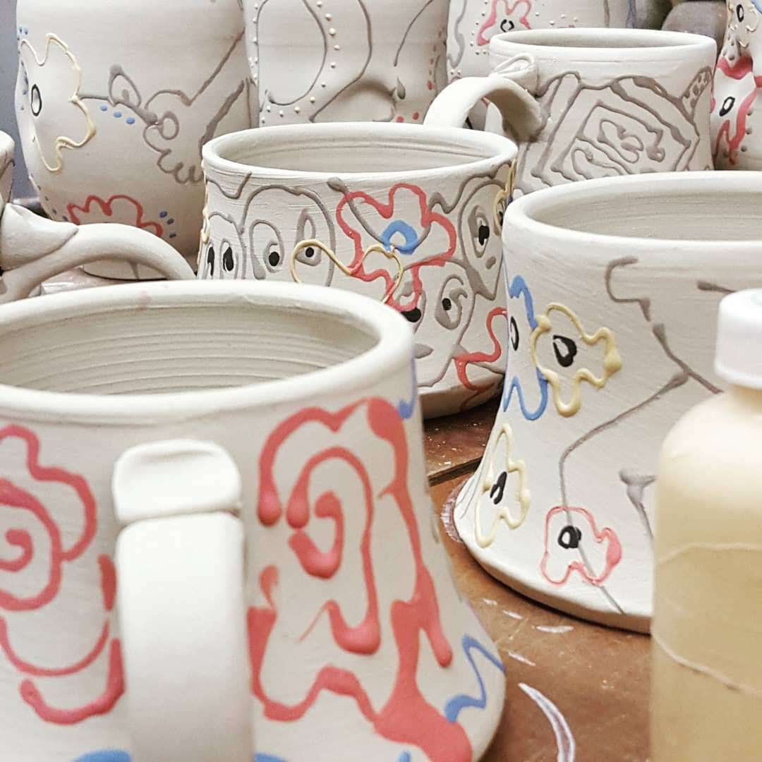 Collection of ceramic mugs with colorful designs on a wooden surface.