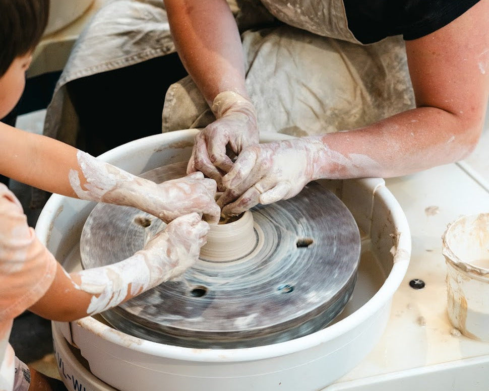 a teacher and a young student working with clay on a pottery wheel - pottery classes for kids in santa monica and los angeles